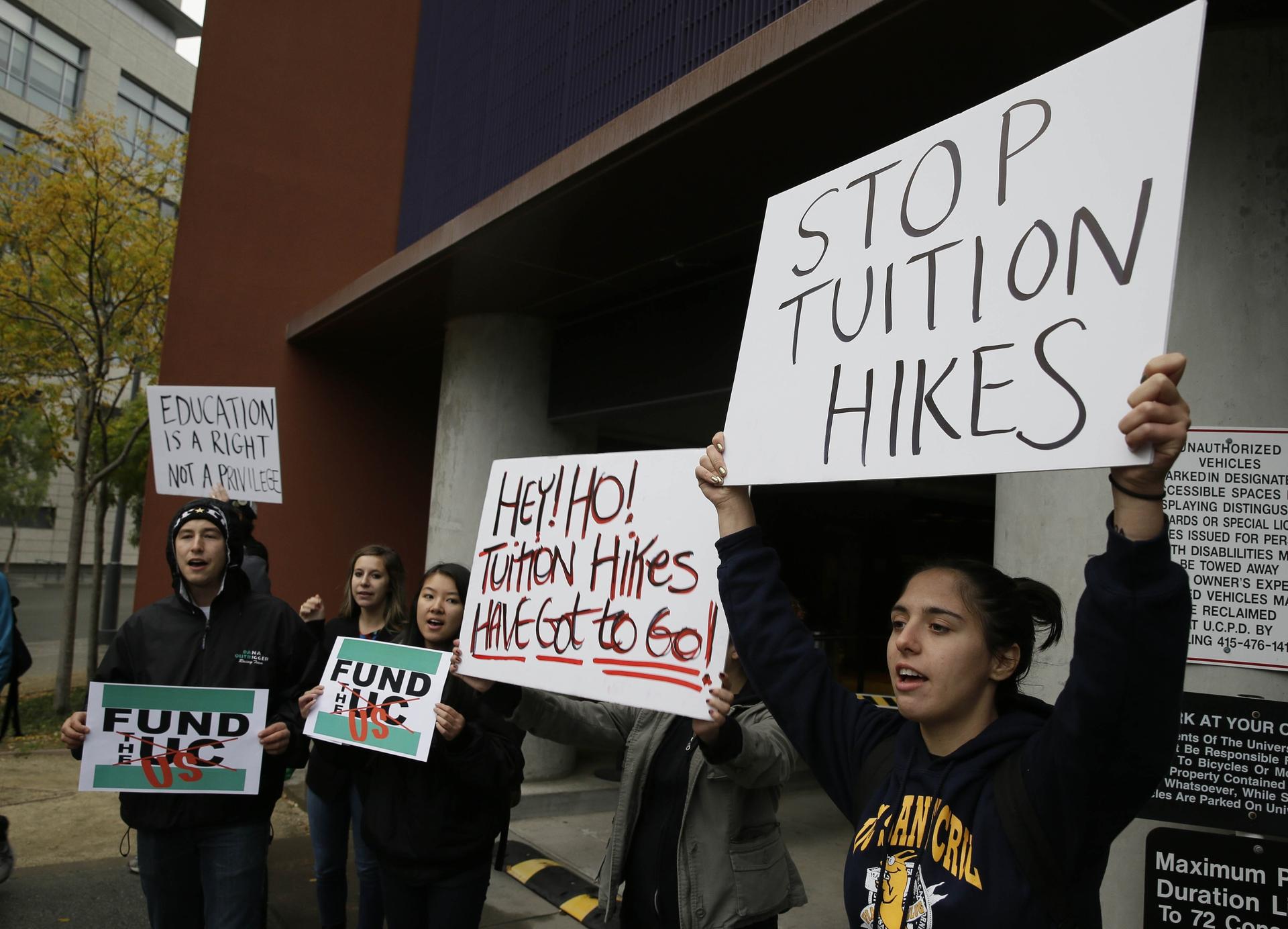 students holding signs protesting tuition hikes