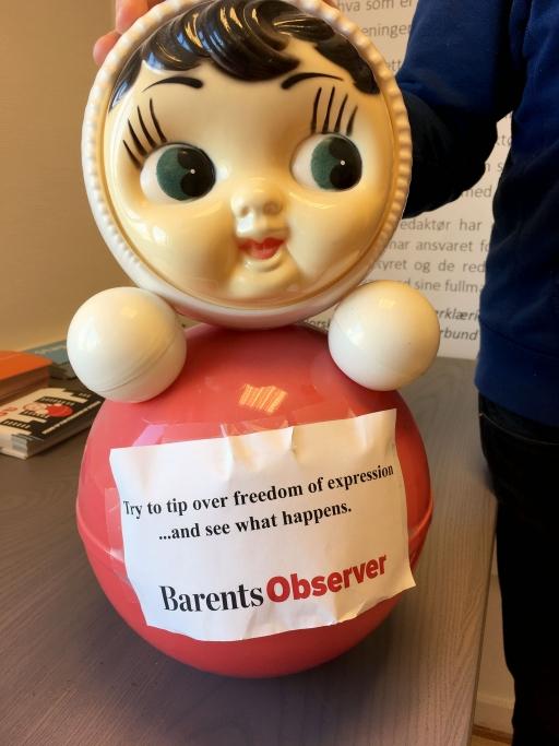 A large bobble-type doll has a paper sign that reads, "Try to tip over freedom of expression ... and see what happens."