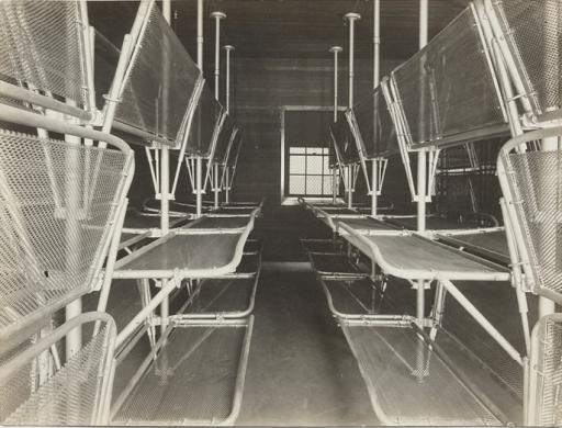 A black and white photo of racks of metal cots. 