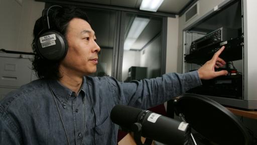 A man wearing headphones speaks into a microphone.