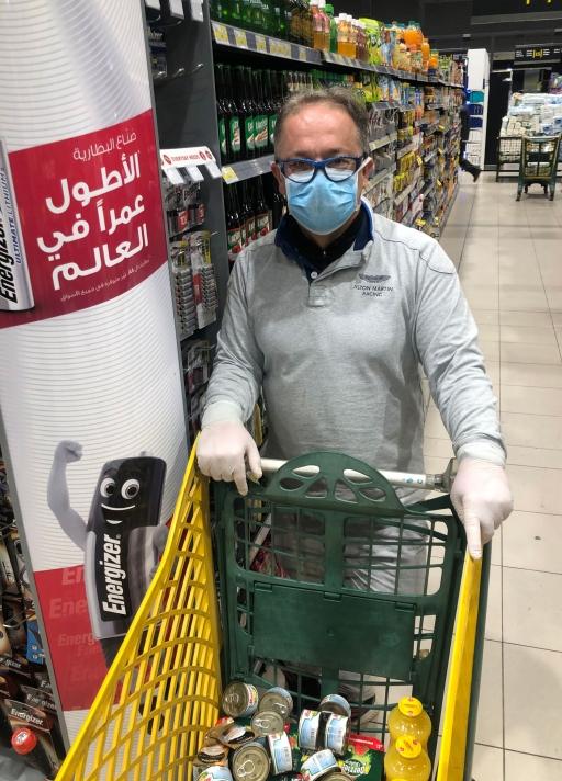 A man with a face mask and gloves shops in a grocery store