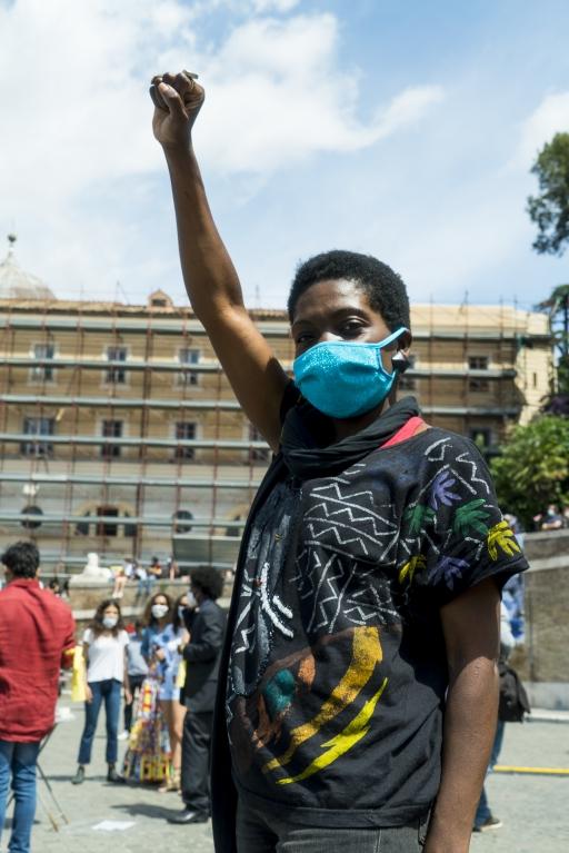 A Liberian woman with short afro wears a blue face mask at a protest 