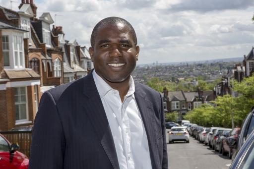 MP David Lammy poses outdoors for a photo wearing a dark suit and white button shirt 