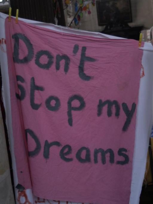 A pink sign reads "Don't stop my dreams" inside a church 