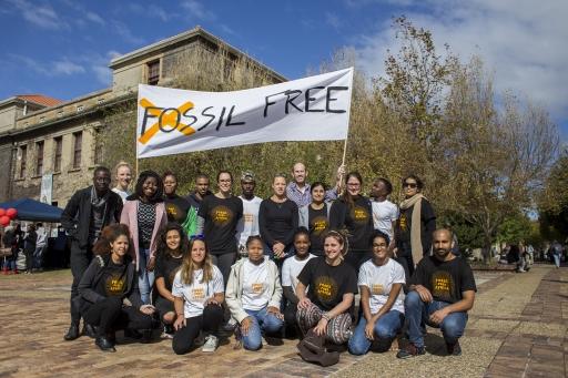 A group of people pose under a banner that reads "Fossil Free"