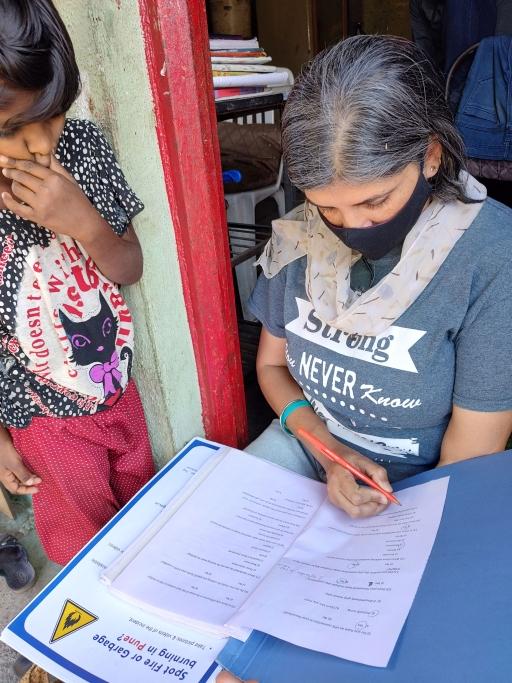 A little girl looks over Anuja Bali's shoulder as she conducts her survey on cooking tools and methods.
