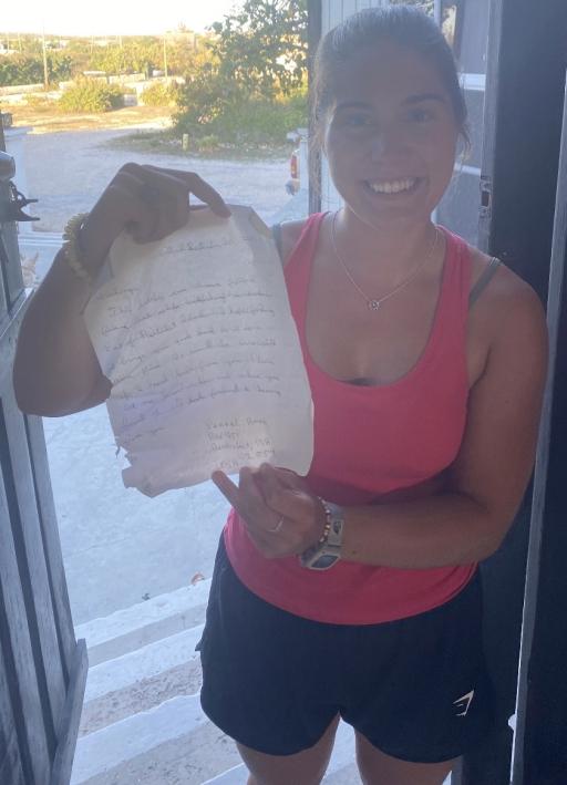 Cassidy Beach holds up the letter she found inside a bottle on South Caicos island that Pennel Ames had thrown into the water in 2004 from Nantucket, 2023.