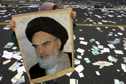 An Iranian girl carries a photo of the late leader of the Islamic revolution, Imam Khomeini, as she walks on a street covered with pre-election leaflets near Azadi Square in Tehran February 11, 2000.