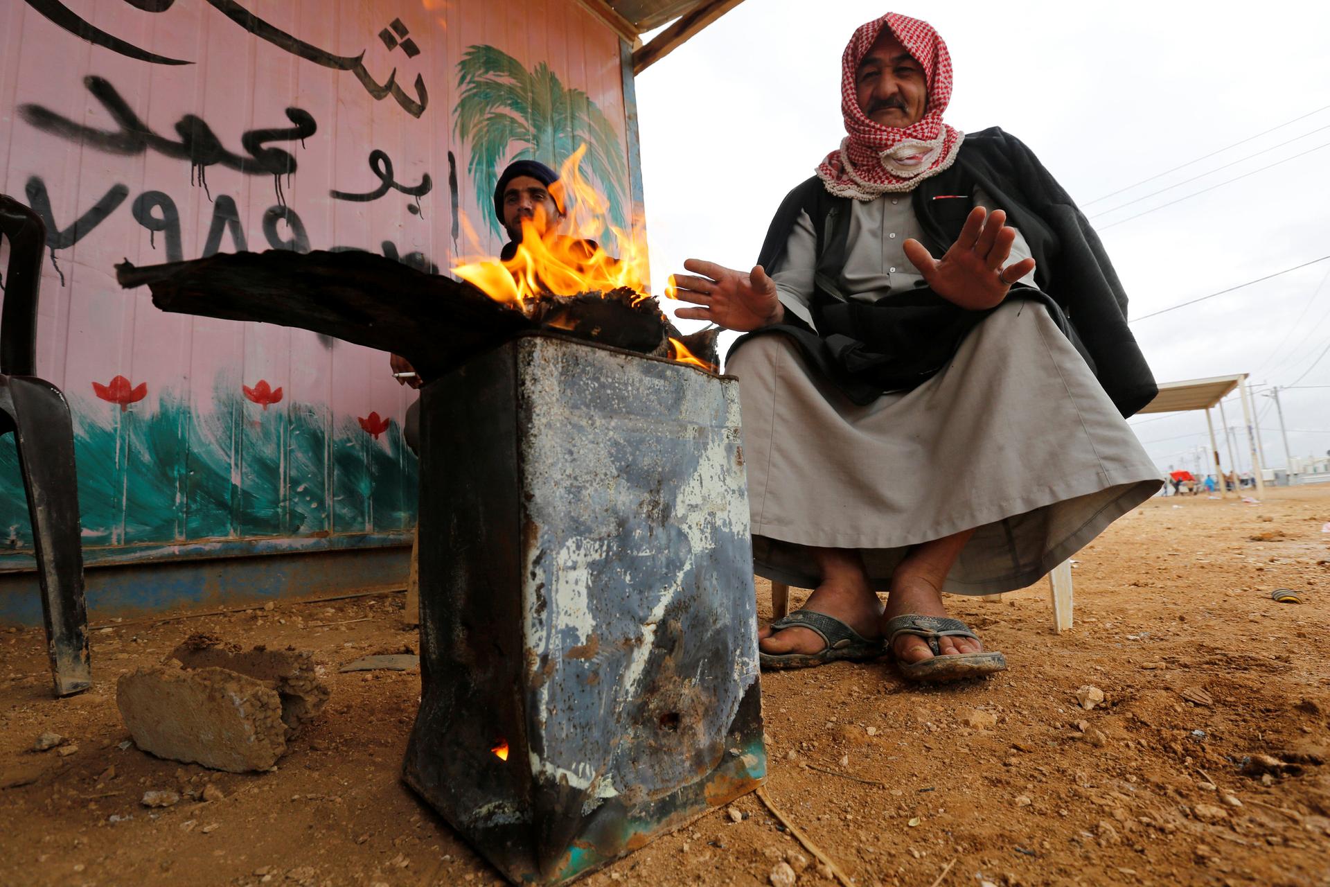 A Syrian refugee man sits by a fire at the Zaatari refugee camp in the Jordanian city of Mafraq, near the border with Syria, Dec. 18, 2016.