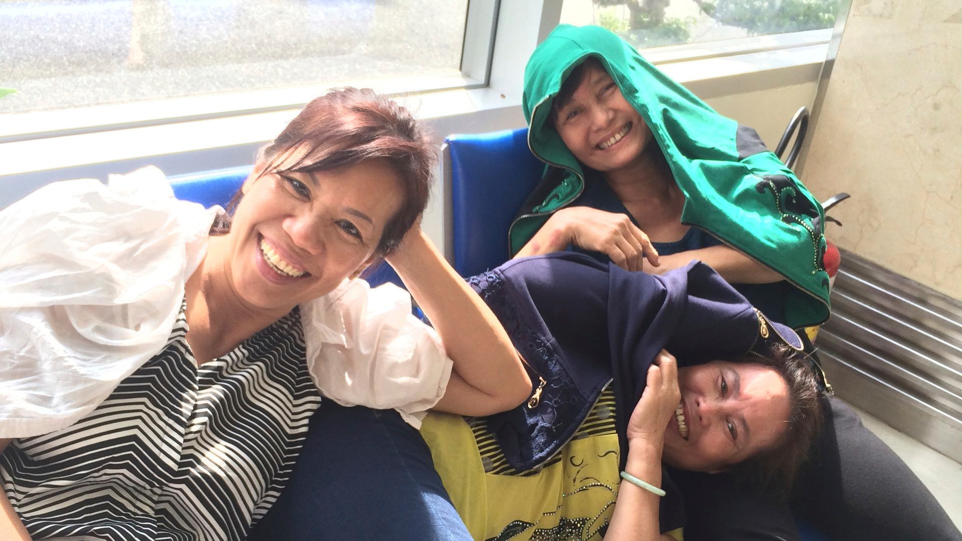 Three women on waiting lounge chairs, smiling.