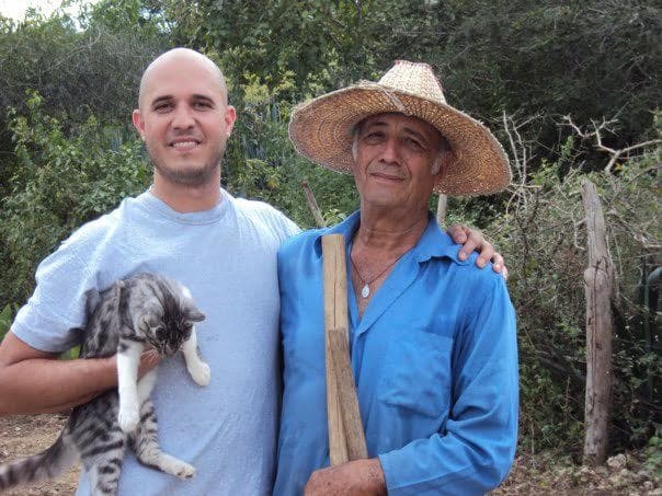 Two men standing with a cat.