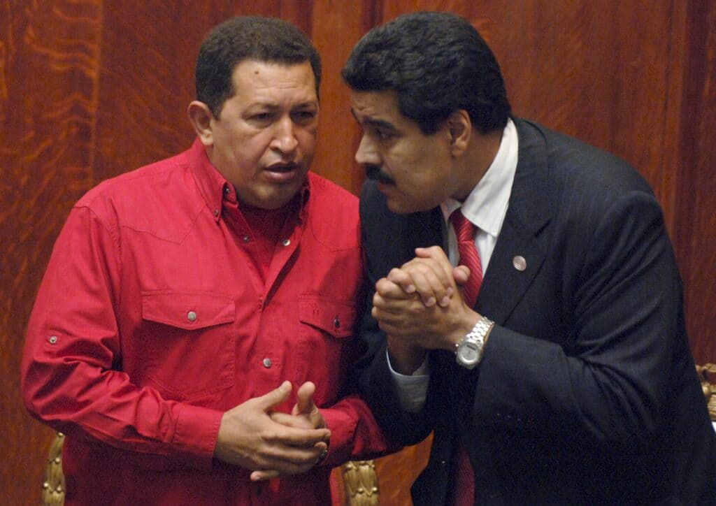Two men sharing a private conversation, one wearing a red shirt, and the other in a black suit.