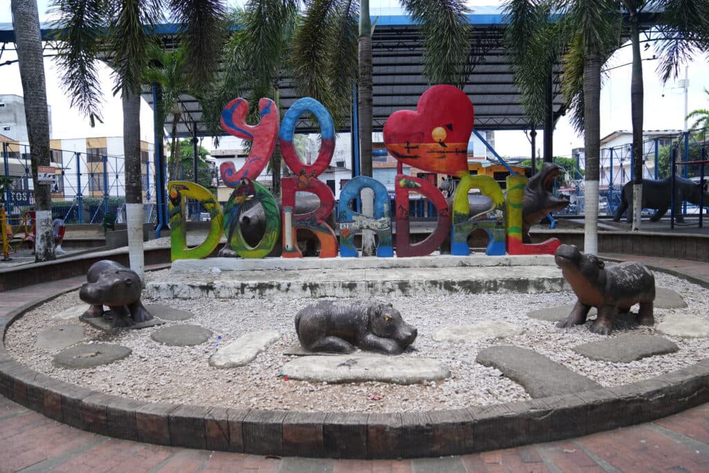 Colorful "Yo Amo Doradal" sculpture surrounded by animal statues in a park setting.