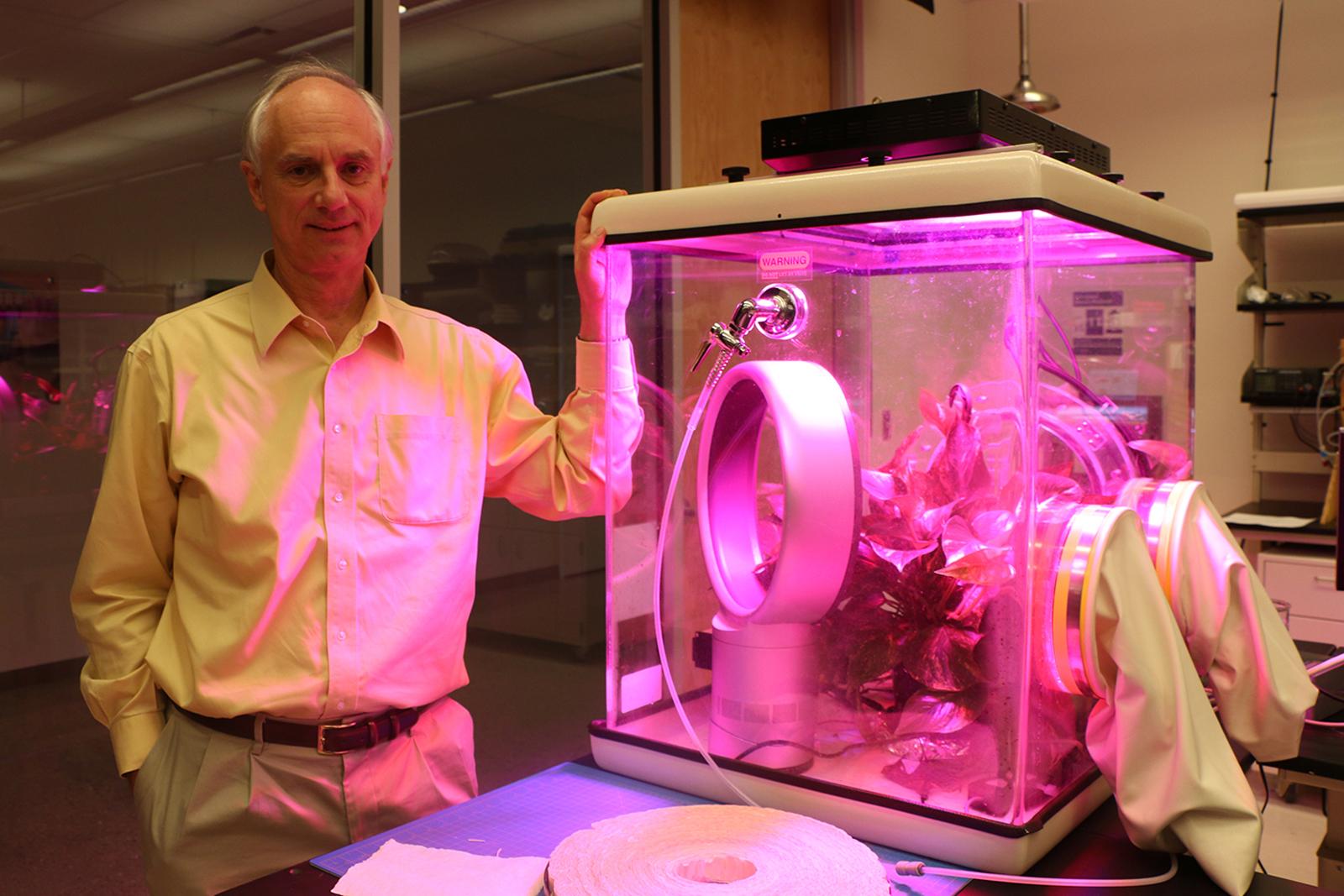 Physicist Klaus Lackner stands beside a miniature greenhouse in his lab at ASU's Center for Negative Carbon Emissions, in which he's testing out the properties of his 