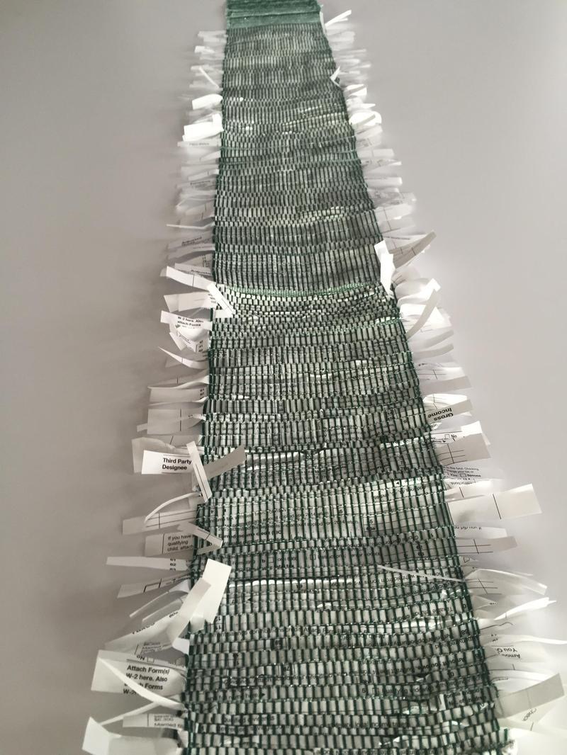 From Cynthia Alberto: 'Weave the Dollar Bills..... 1040 forms cut into strips woven on a 4 harness, 4 thareadles, Schacht floor loom. Warp - cotton Weft - 1040 forms Size: 8' wide x 36' length'