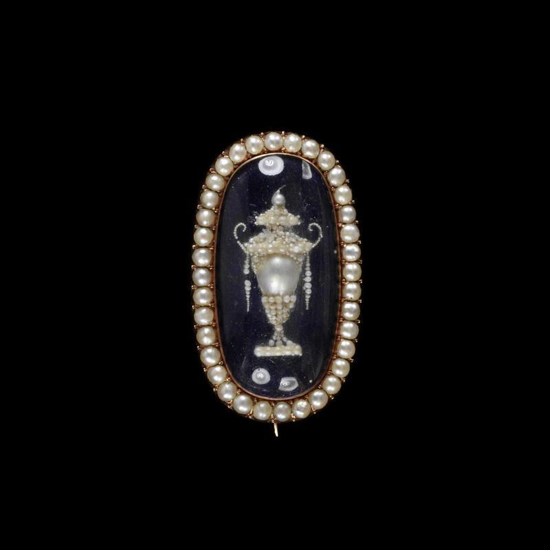 A gold brooch featuring a funeral of enamel, pearls, and hair