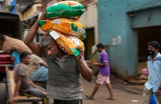 A porter carries sacks of imported food items at a market place in Colombo, Sri Lanka